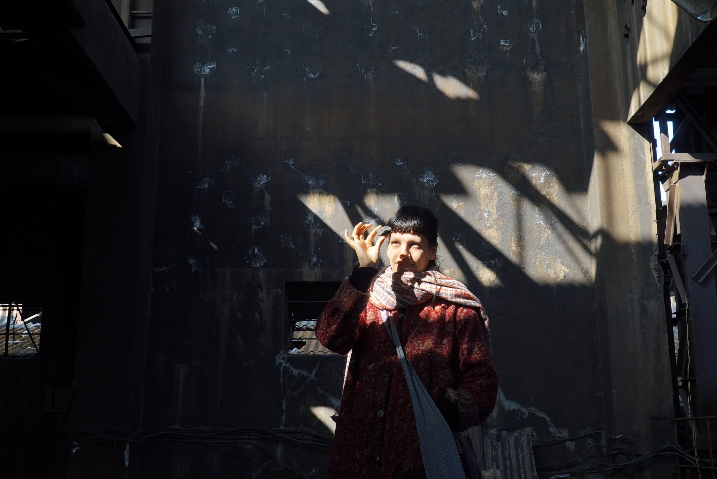 A person posing in striking shafts of light inside the abandoned factory