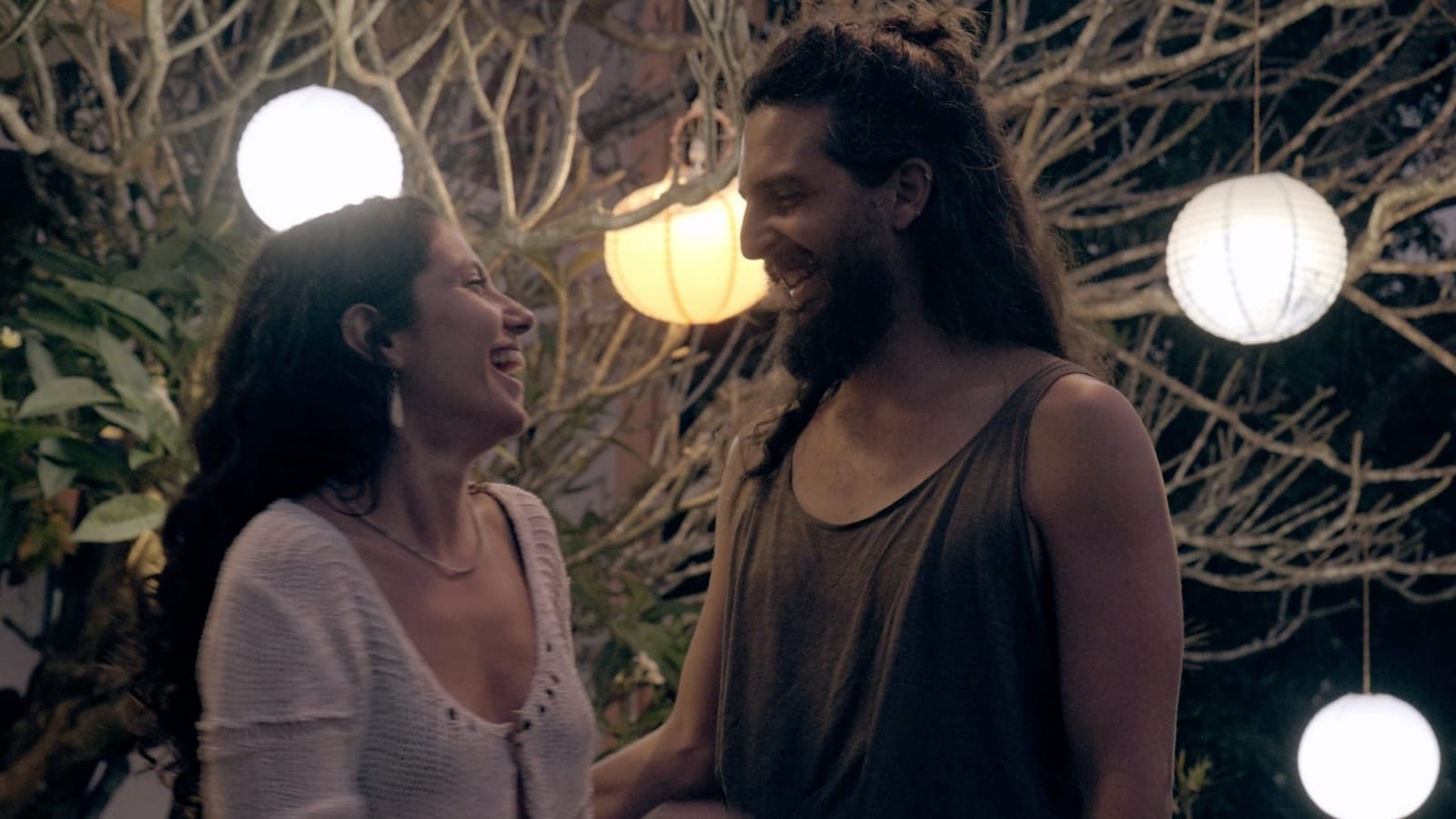 Two residents laughing under warm paper lanterns