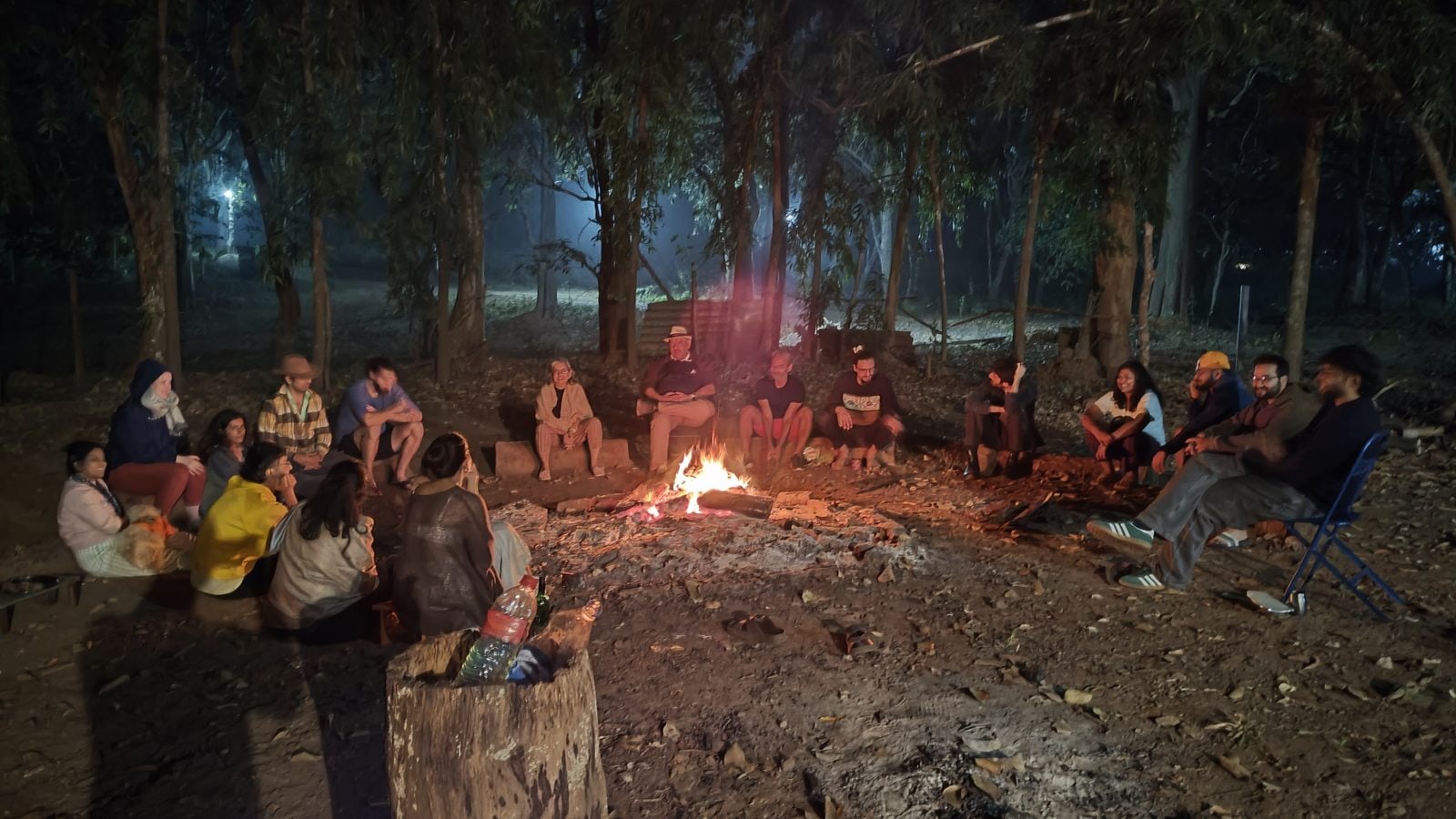 The whole group seated in a circle around the fire in the forest