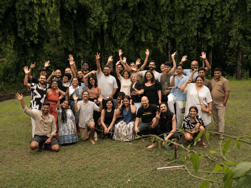 The Jungli community together on the grass, hands in the air